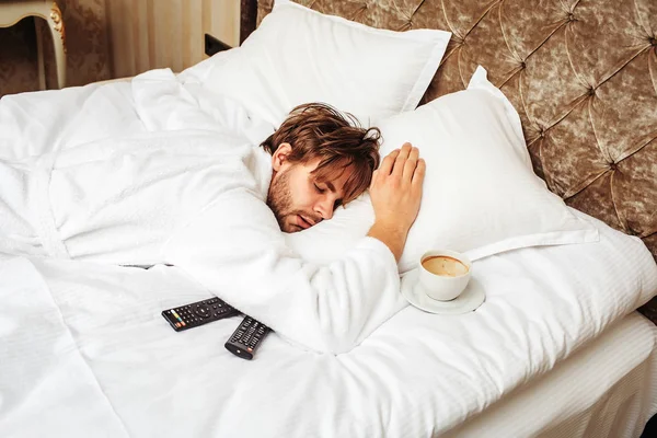 bearded man on bed with remote