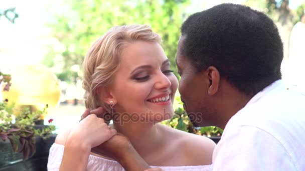 Casal de raça mista beijando em um café no dia de verão. feliz afro-americano interracial casal no um data ao ar livre — Vídeo de Stock