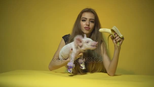 Девушка кормит свинью бананом — стоковое видео