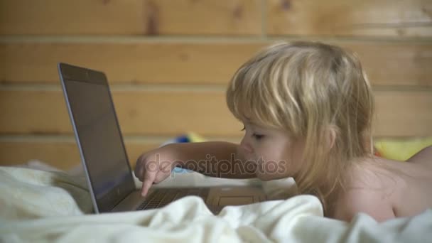 Çocuk iki yıl onun mide ve bilgisayar eserlerinde yatakta yatan eski. Akıllı çocuk veya çocuk iş veya oyun için laptop kullanıyor — Stok video