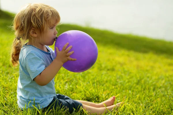 Cute baby boy with violet toy balloon — Stock Photo, Image