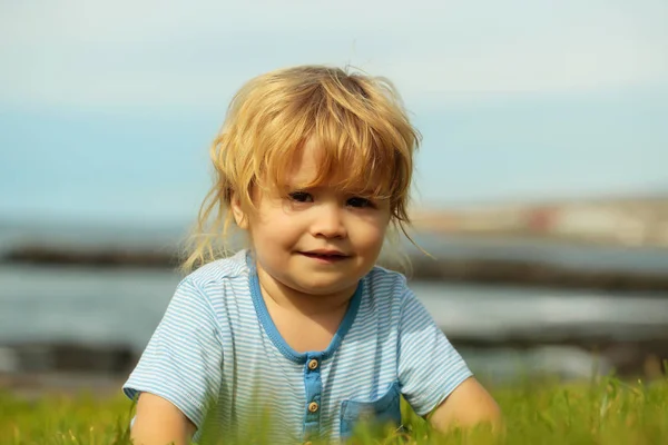 Cute baby chłopiec siedzi na zielonej trawie — Zdjęcie stockowe