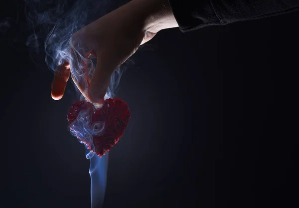 Manlig hand med dekorativa alla hjärtans dag rött hjärta i rök — Stockfoto