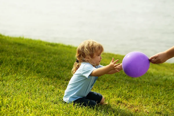 Милый мальчик ловит фиолетовый воздушный шарик — стоковое фото