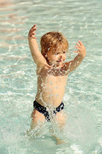Lindo bebé niño rocía agua en la piscina al aire libre —  Fotos de Stock
