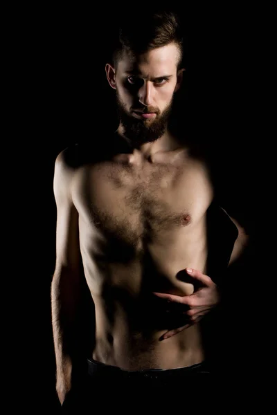 slim bearded man with thin bare torso isolated on black