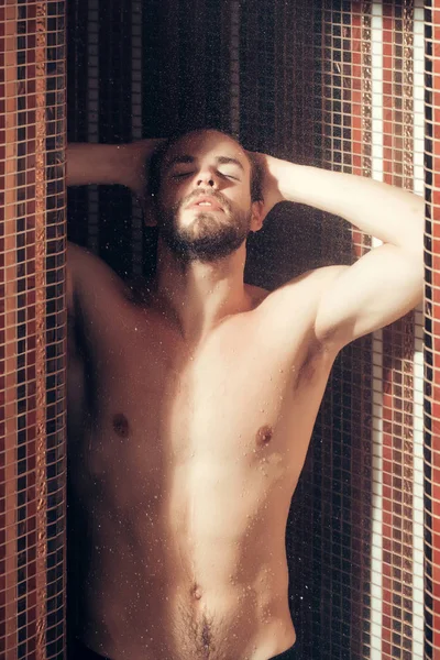 muscular handsome wet man in shower under water