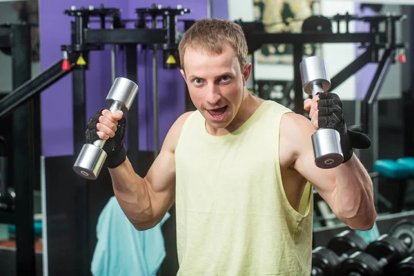 handsome happy sexy muscular man training with metallic dumbbells