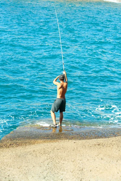 Stilig fiskare fiskar med fiskespö — Stockfoto