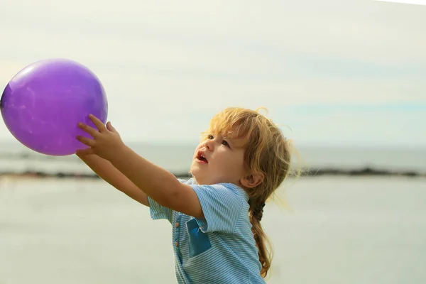 Ładny chłopczyk w ręce trzyma balon fioletowy zabawka — Zdjęcie stockowe