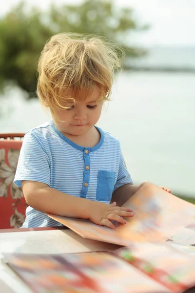 Menino bonito lê cartão de menu — Fotografia de Stock