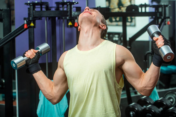 handsome happy sexy muscular man training with metallic dumbbells