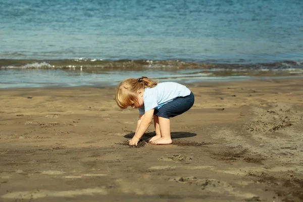 Lindo bebé juega con arena en la playa de arena — Foto de Stock