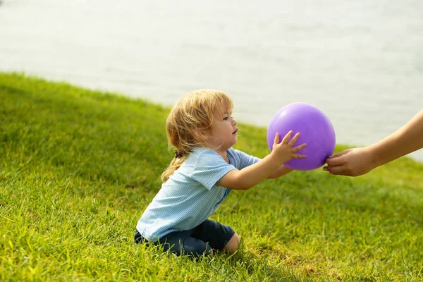 Bonito bebê menino pega violeta brinquedo balão — Fotografia de Stock