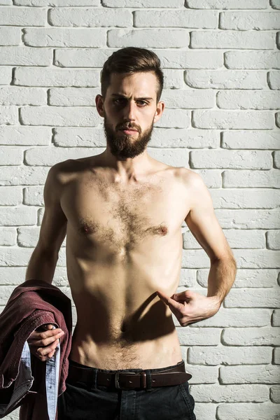 slim bearded man with thin bare torso on brick background