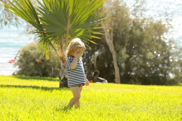 Lindo bebé niño en camiseta rayada camina sobre hierba verde —  Fotos de Stock