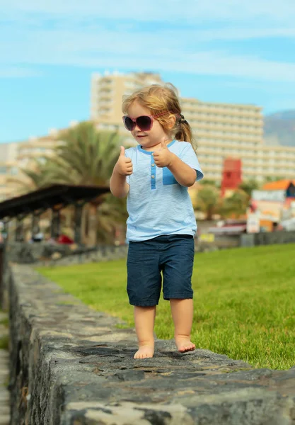 Roztomilý šťastný chlapeček v sluneční brýle ukazuje palec nahoru gesto — Stock fotografie