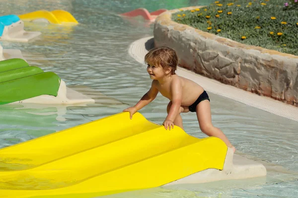 Gelukkig schattige babyjongen speelt op gele glijbaan — Stockfoto