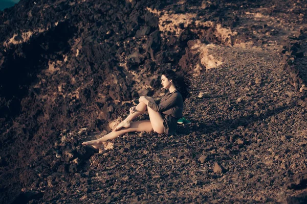 漂亮的女孩坐在棕色的岩石表面上 — 图库照片