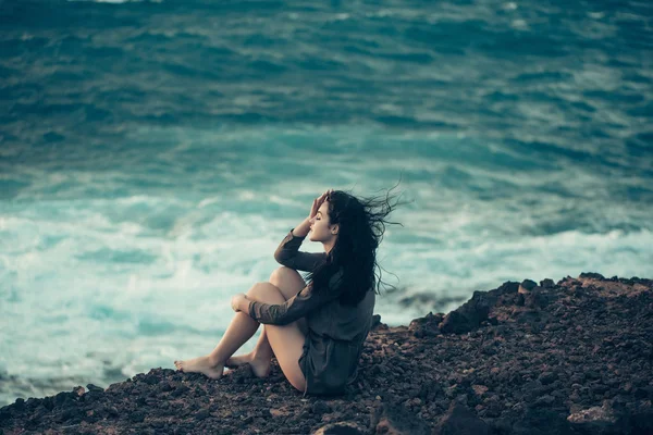 Menina bonita senta-se na encosta da montanha — Fotografia de Stock