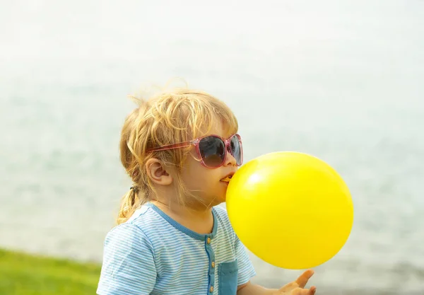 Bonito menino brinca com balão de brinquedo amarelo — Fotografia de Stock