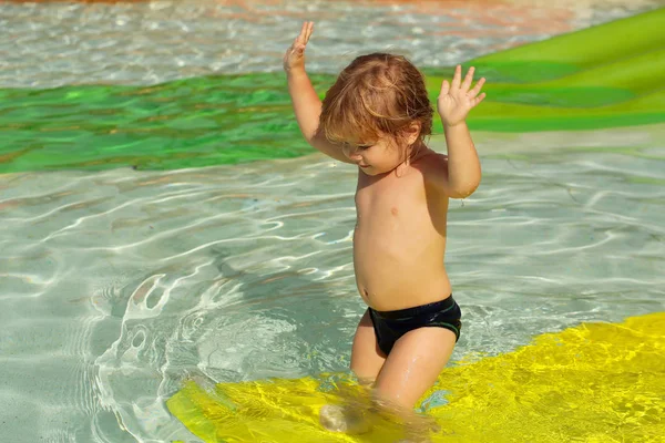 Feliz menino bonito joga no slide de água amarelo — Fotografia de Stock
