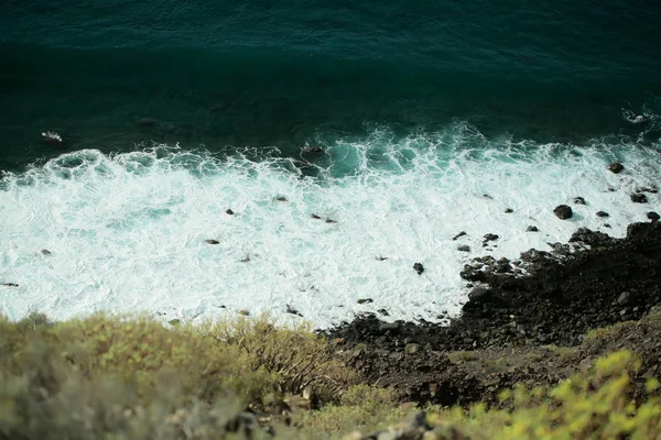 Vacker akvamarin havet vågor krasch mot svarta stenar — Stockfoto