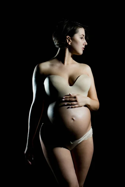 Pretty pregnant woman with round belly isolated on black — Stock Photo, Image