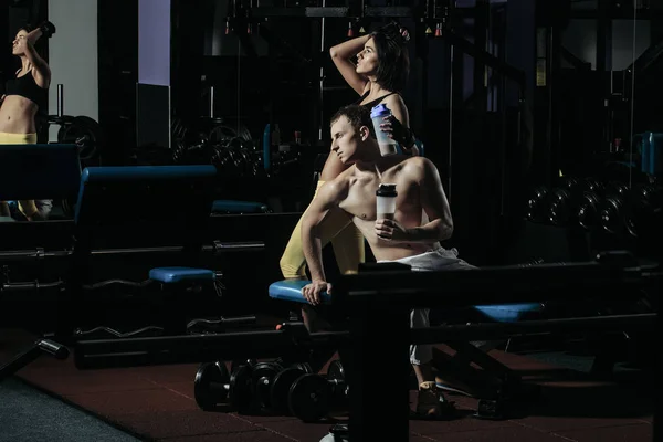 Kaslı adam ve spor salonu eğitmen şişeyle seksi kız — Stok fotoğraf