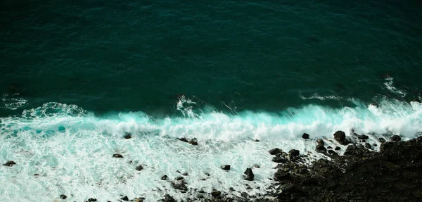 Belas ondas aquamarinas do mar colidem contra rochas negras — Fotografia de Stock