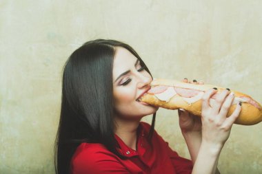 seksi güzel esmer gülümseyen kadın koca sandviç ya da hamburger yiyor