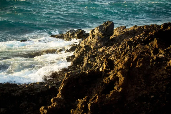 美丽的蓝色大海风浪飞溅对棕色石岸 — 图库照片