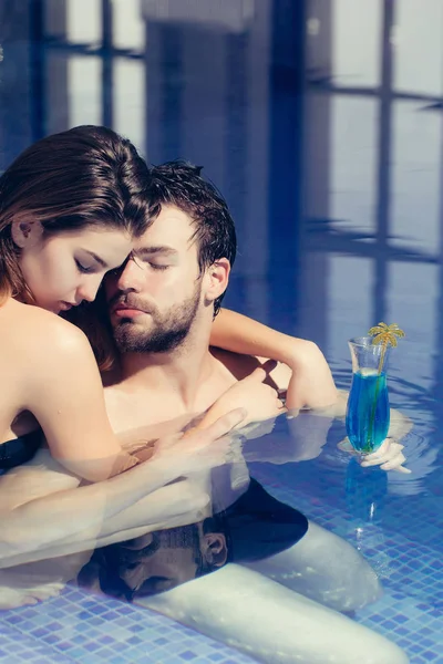 Muskularny mężczyzna i kobieta sexy w niebieski basen z koktajl — Zdjęcie stockowe