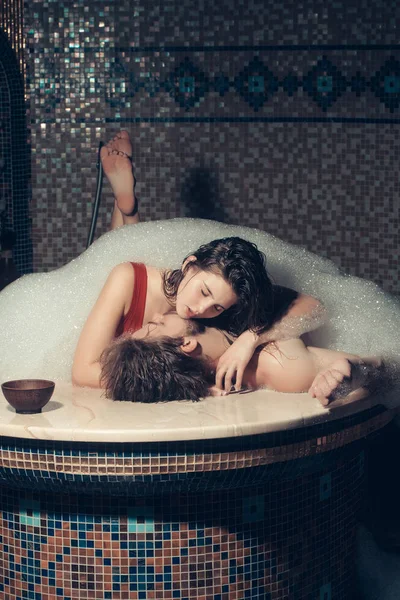 Μυώδης άνδρας και σέξι γυναίκα τοποθέτηση σε μπάνιο με αφρό — Φωτογραφία Αρχείου