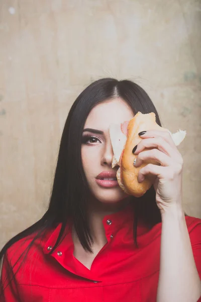Sexy pretty brunette serious woman eats big sandwich or burger — Stock Photo, Image