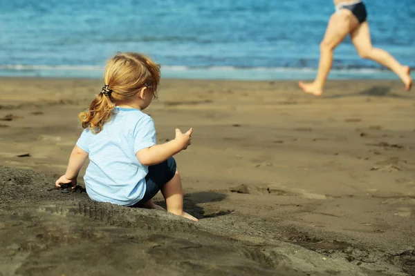 Lindo bebé niño se sienta en la arena en la playa de arena —  Fotos de Stock