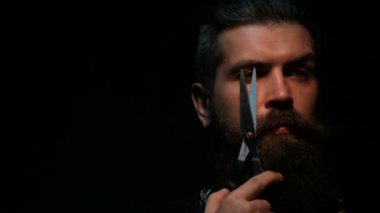 Keskin makas, sakallı adam, tehlikeli oyunlar. Güzellik Salonu ya da berber dükkanı. Sakallı adam bıçakla bir oyun oynuyor. Sakallı çekici Kuaför