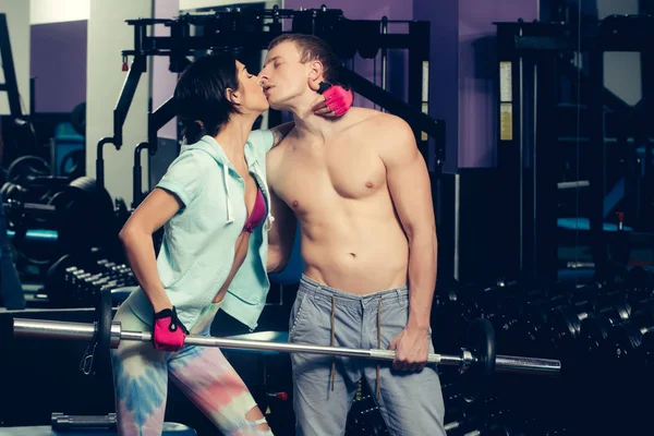 Muskulöse Mann und Mädchen in der Turnhalle mit Küssen mit Langhantel — Stockfoto
