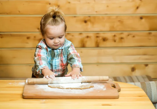 Cute child cooking with dough, flour and wood rolling pin — Stock Photo, Image