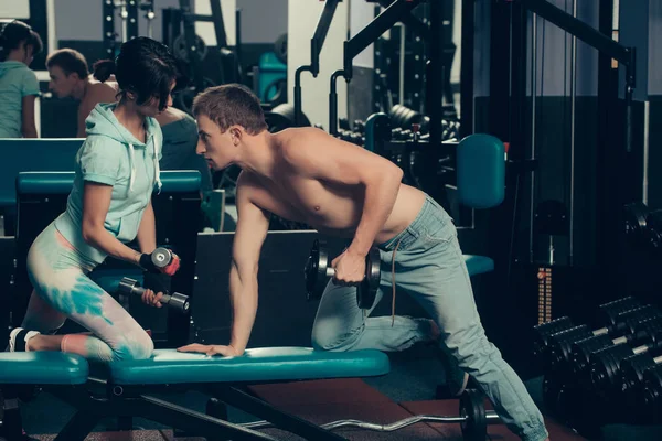 Muscoloso uomo e ragazza in palestra con manubri — Foto Stock