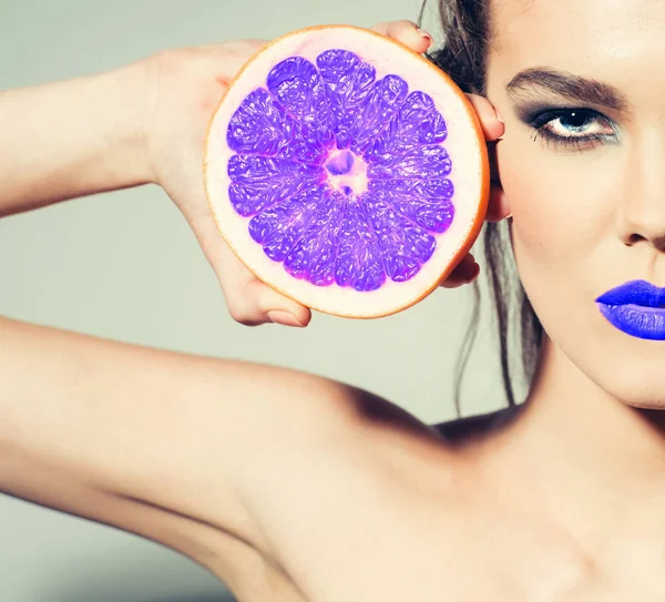 Mooi meisje met blauwe lippen en violet grapefruit — Stockfoto