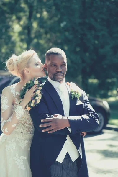 Hübsches Mädchen oder süße Braut umarmt gutaussehenden afrikanisch-amerikanischen Bräutigam — Stockfoto