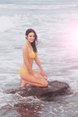 Kayanın üzerinde oturan sexi sarı mayo oldukça mutlu kız