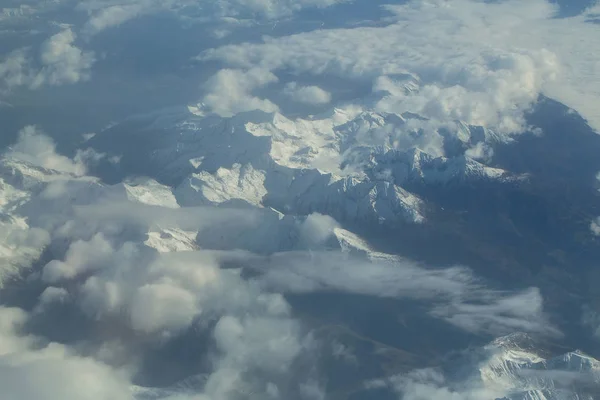 Idyllic snowy mountain peaks under clouds from plane — Stock Photo, Image