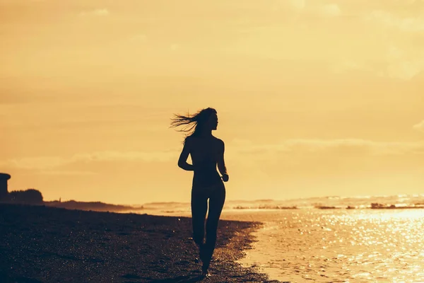 Jolie fille en maillot de bain jaune courant sur une plage de sable fin — Photo