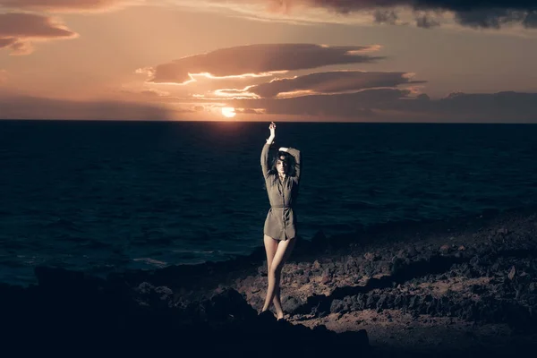 漂亮的女孩在多岩石的海岸海上田园日落期间 — 图库照片