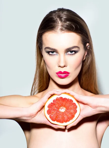 Söt flicka täcker bröstet med apelsin grapefrukt — Stockfoto