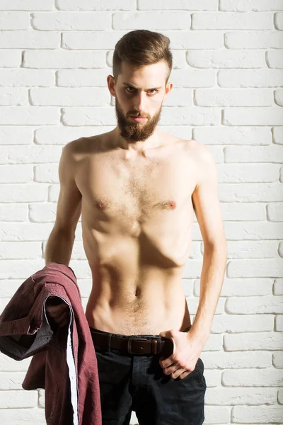 slim bearded man with thin bare torso on brick background