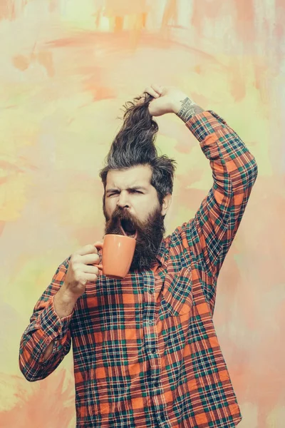 Zły Brodaty mężczyzna trzymając włosy fringe i orange cup — Zdjęcie stockowe