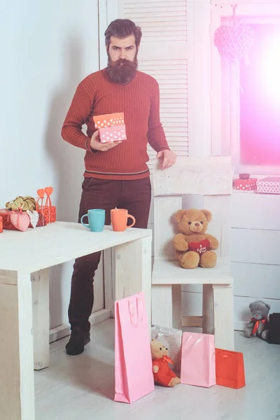 Бородатый мужчина с подарочными коробками за столом с чашками — стоковое фото